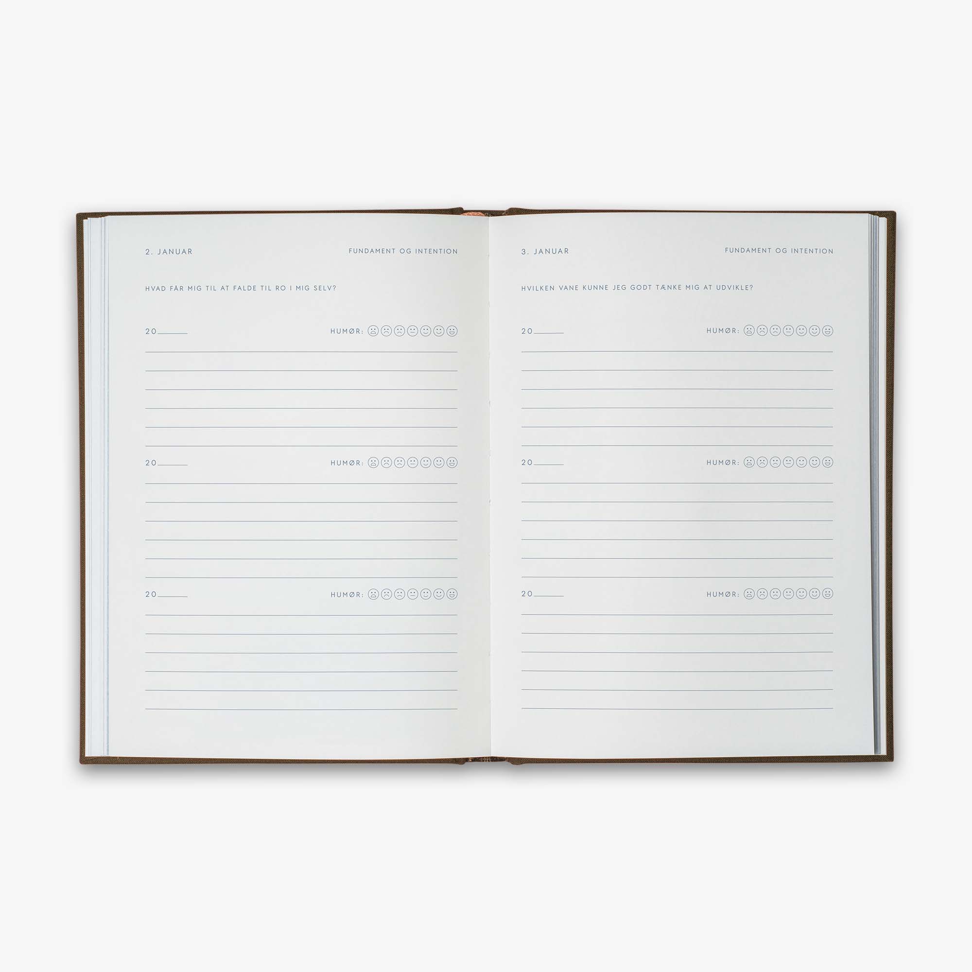 Open book from our Three Year Journal (Treårsdagbogen) with the daily prompts on a white background