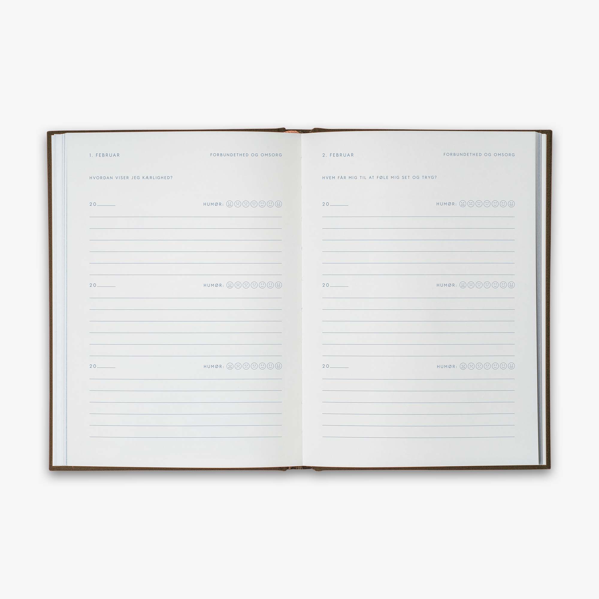 Open book from our Three Year Journal (Treårsdagbogen) with the daily prompts on a white background