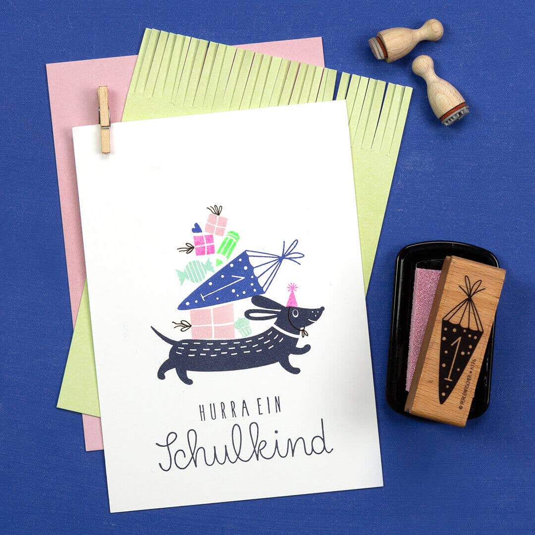 Card with a dachshund illustration and text on a blue background with stationery items.
