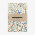 Notebook with a colorful animal pattern and 'petit gramme' branding on a white background