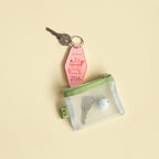 Green mesh pouch with keys in on a beige background