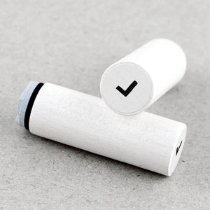 White wooden rubber stamps with a black band and check mark on a gray surface