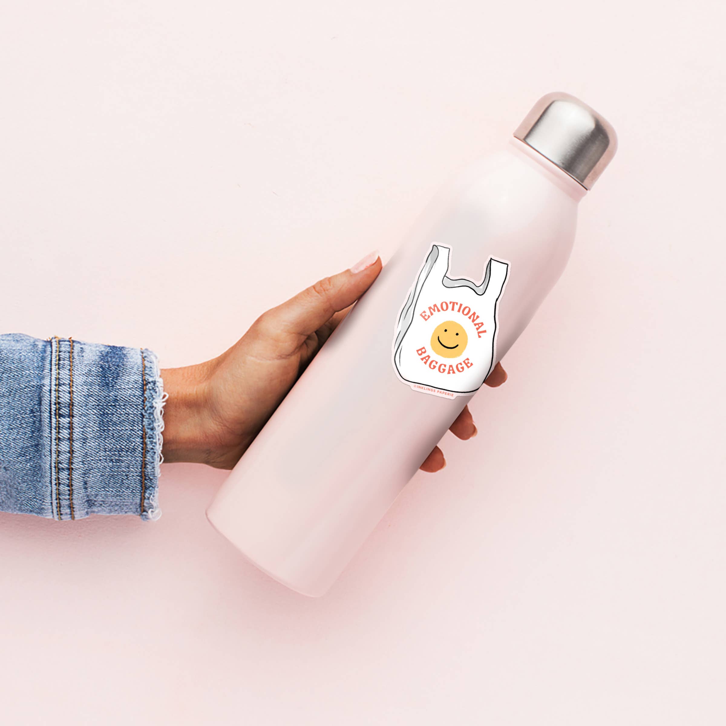 Person holding a pink water bottle with a smiley face and text design on a light pink background