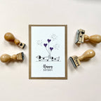 Framed birthday card with dachshunds and hearts, surrounded by wooden stamps on a light background