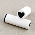 Two wooden rubber stamps with black heart symbols on a beige background