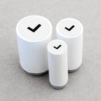 Three wooden rubber stamps with black check marks on a gray background
