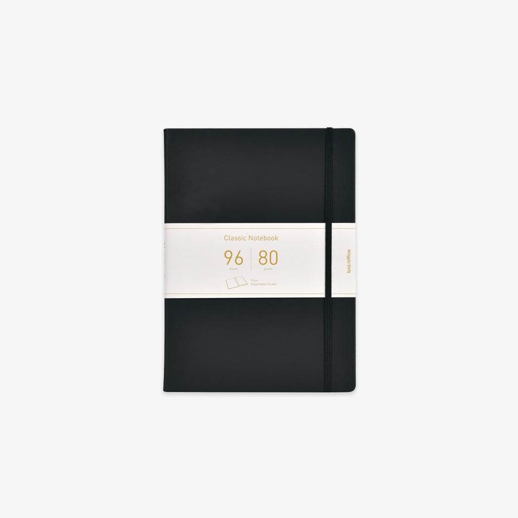 A black hardcover notebook with an elastic closure band and a white paper band around the middle, featuring gold text that reads 'Classic Notebook 96 sheets and 80gsm'.