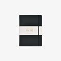 A black hardcover notebook with an elastic closure band and a white paper band around the middle, featuring gold text that reads 'Classic Notebook 96 sheets and 80gsm'.