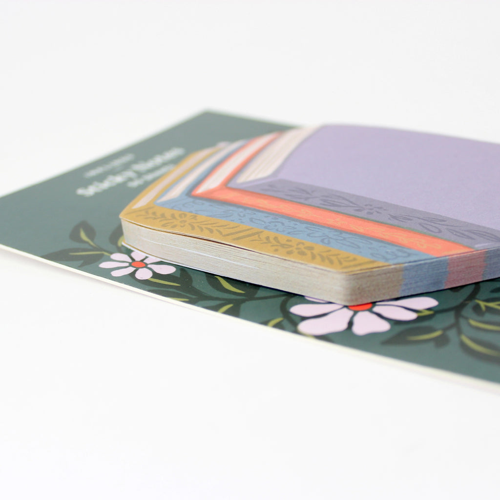 Stack of colorful book stack-shaped sticky notes with floral design on a white background
