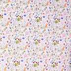 A close-up of a white fabric with a dense, all-over watercolor floral print featuring pink, blue, green, orange, and red wildflowers and leaves.
