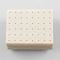 Wooden stamp with a square of dots on a gray background