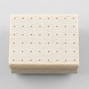 Wooden stamp with a square of dots on a gray background