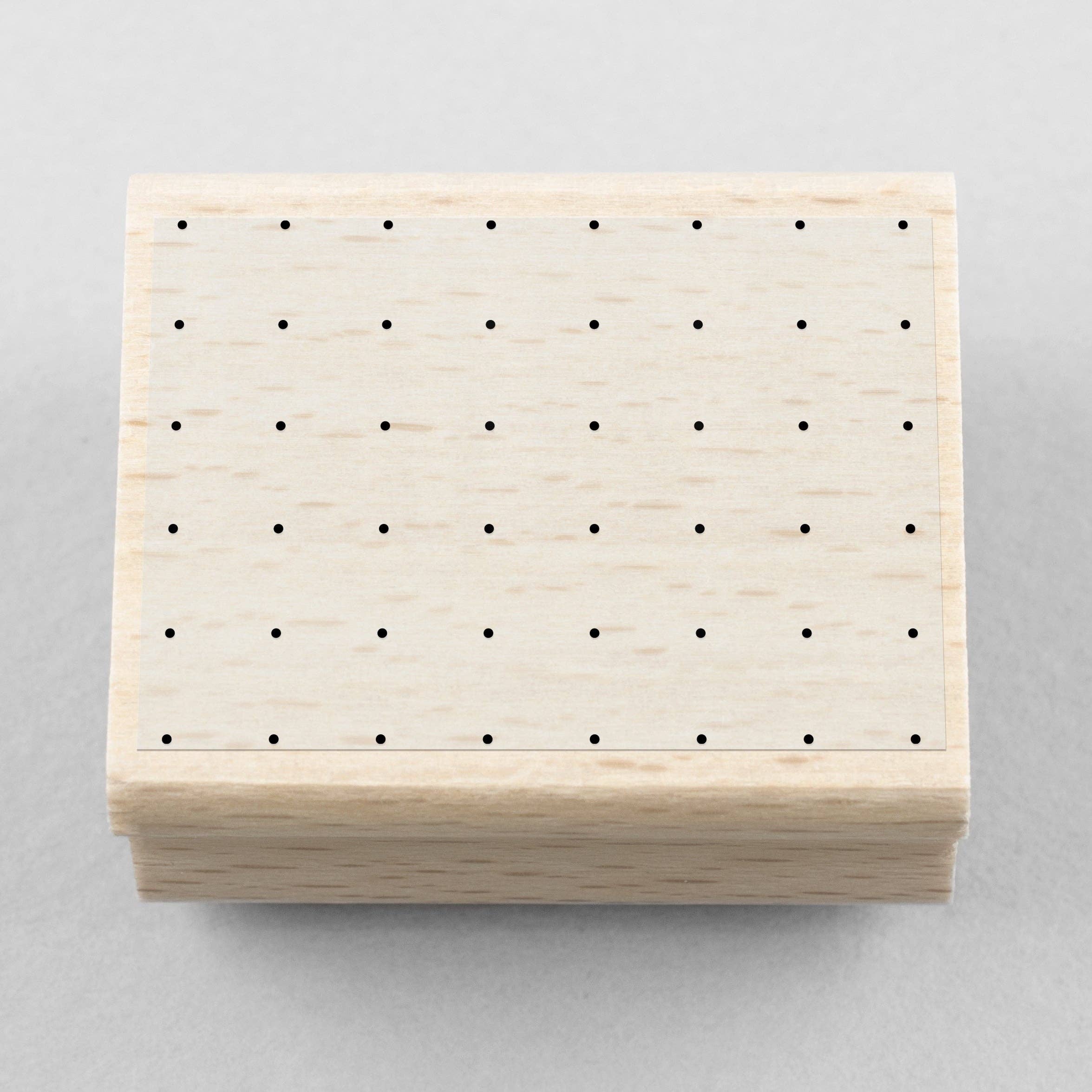 Wooden stamp with a square of dots on a gray background