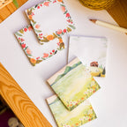 Set of sticky notes with floral and landscape designs on a white surface.