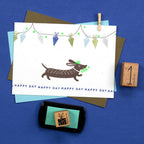 Greeting card with a dachshund illustration and decorative elements on a blue background