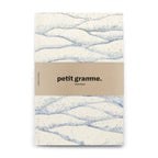 Notebook with wavy pattern and 'petit gramme' branding on a white background
