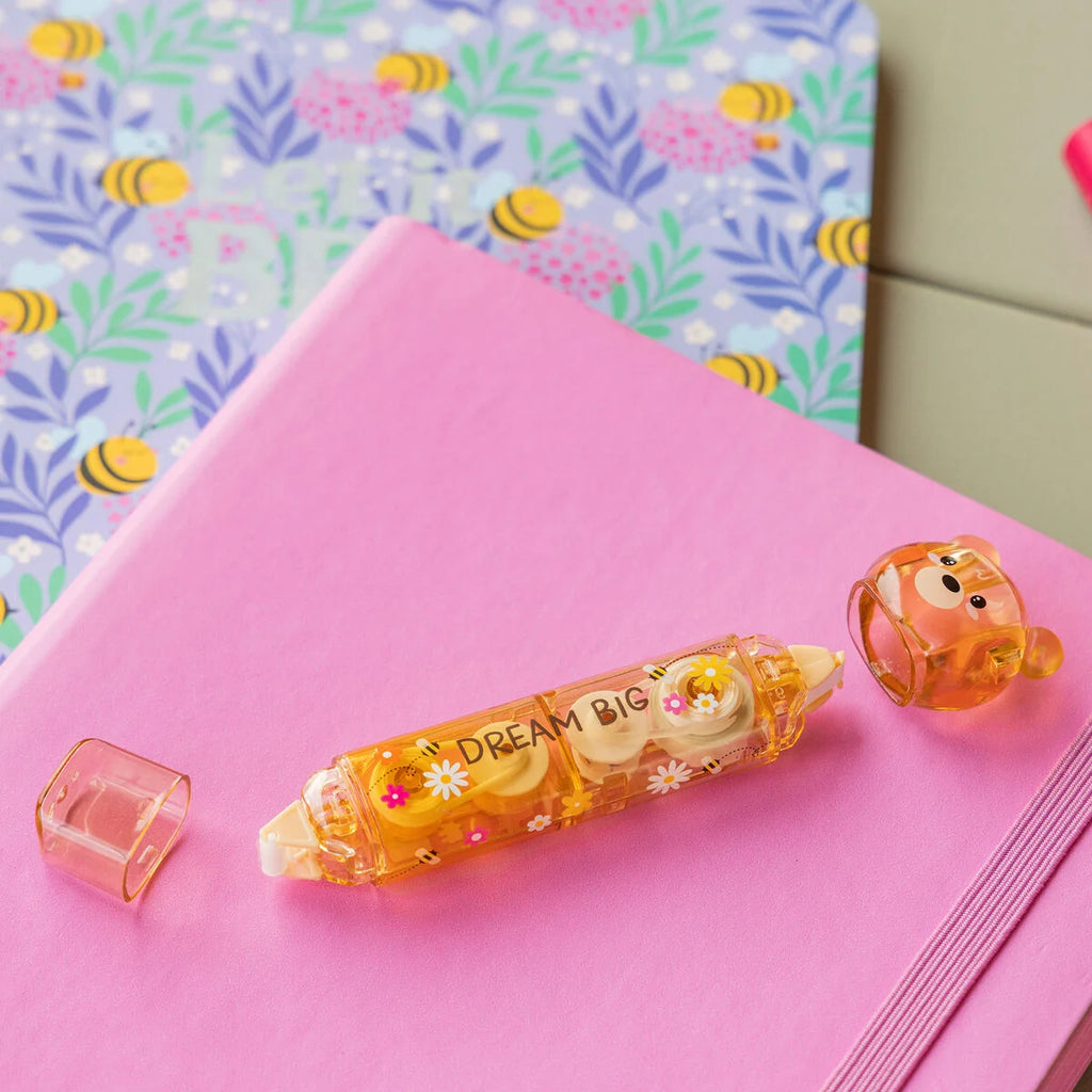 Decorative brownish correction and glue tape with 'Dream Big' text on a pink notebook with a floral patterned background.