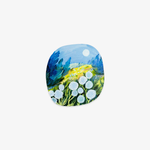 A square cushion cover featuring a colorful landscape painting with blue mountains, a yellow field, and white flowers under a light blue sky.