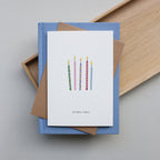 Greeting card with birthday candles design and 'birthday wishes' text on a blue box with brown paper