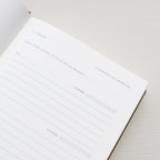 Open notebook with a page showing text and emoji icons from 'Treårsdagbogen' on a light background