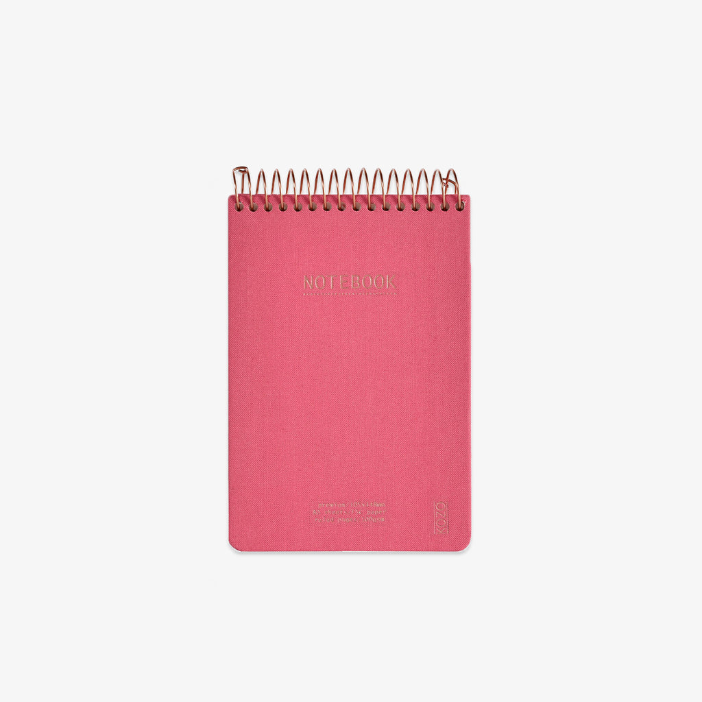 Pink notebook with gold spiral binding on a white background