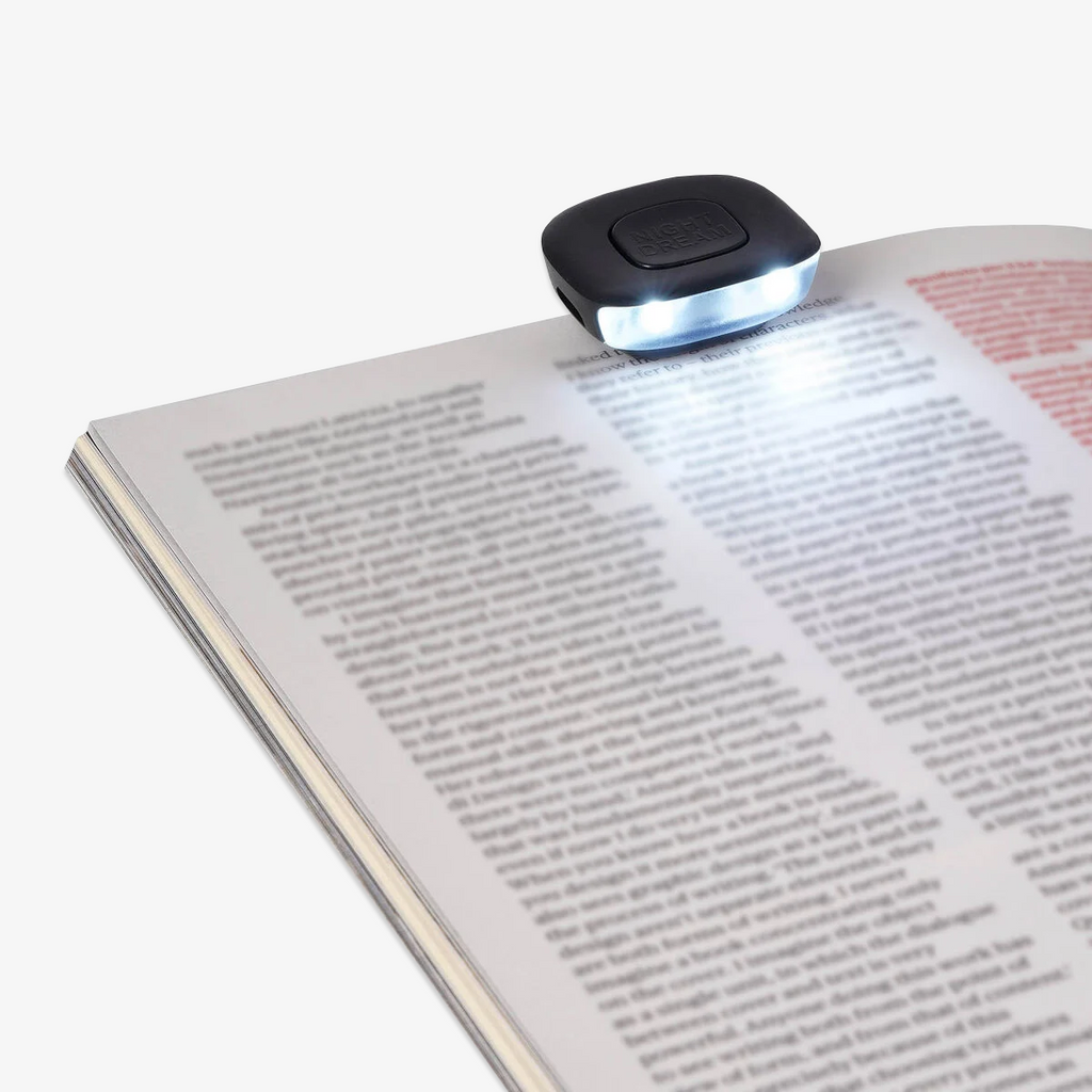 Book light illuminating an open book on a white background