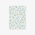 A rectangular sheet of paper with a repeating floral pattern of light blue flowers and green leaves on an off-white background, shown against a light gray studio backdrop.