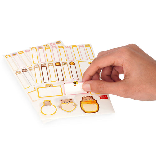 Hand holding a sheet of decorative labels with animal designs on a white background