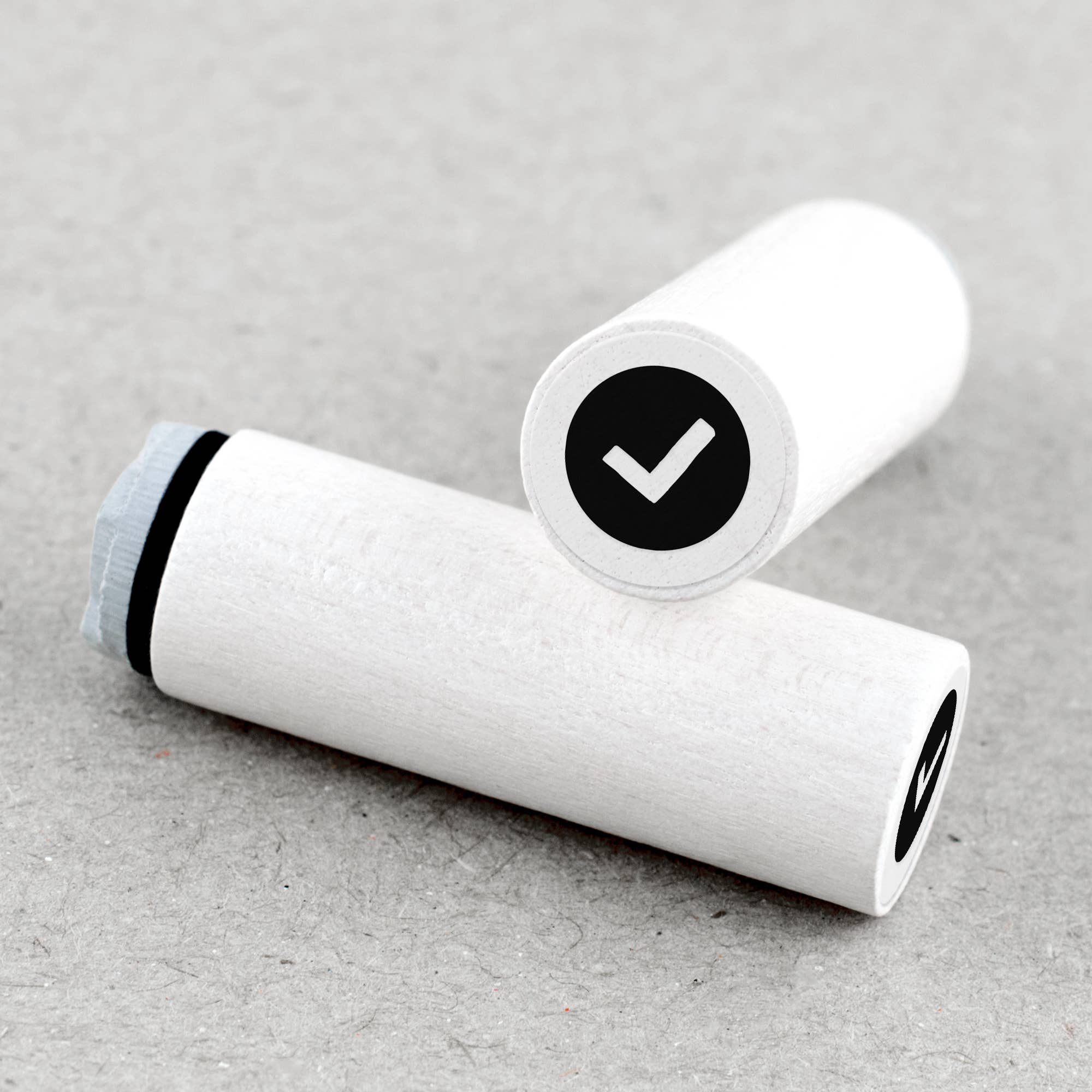 Two white rubber stamps with check symbols on a beige background