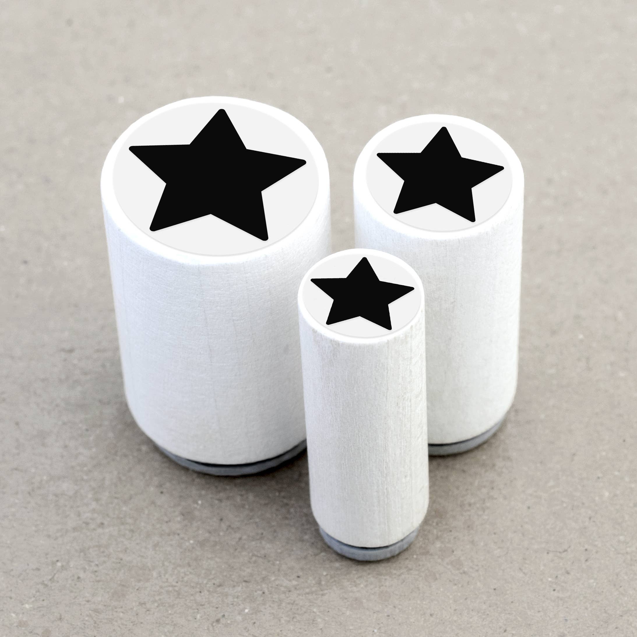 Three wooden rubber stamps with black star designs on a gray background