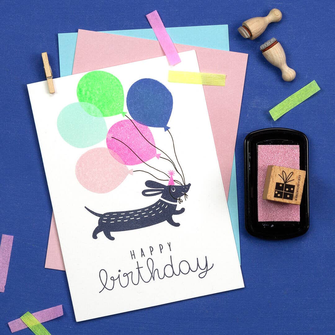 Birthday card with a dog and balloons on a blue background with stamps.