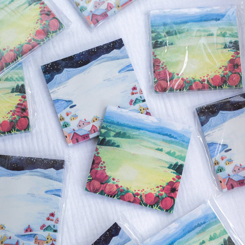 Sticky notes with scenic and floral designs on a white surface