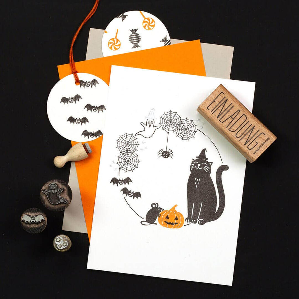 Halloween-themed invitations with black and orange design elements on a dark background.