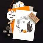 Halloween-themed invitations with black and orange design elements on a dark background.
