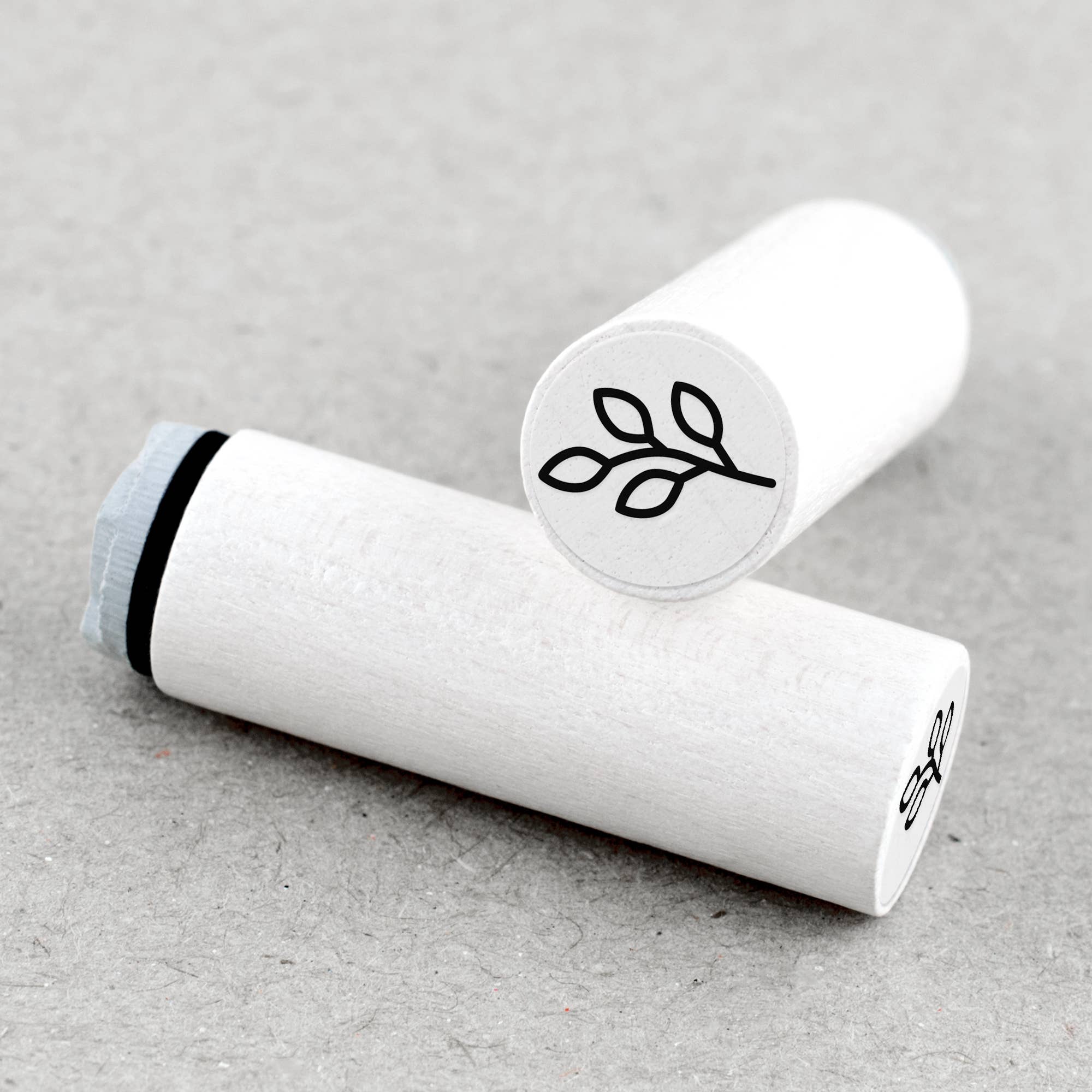 Two white rubber stamps with plant symbols on a beige background